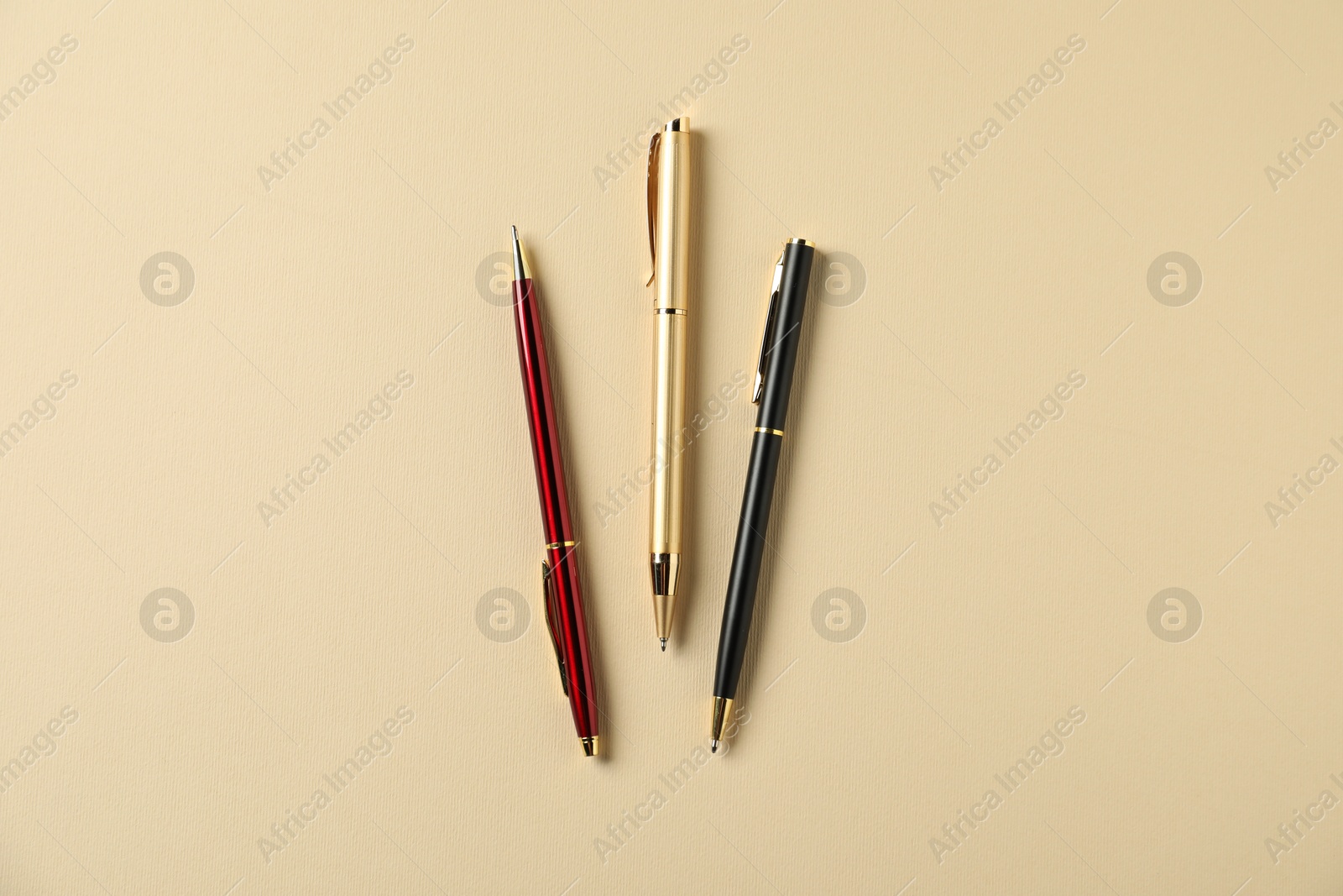 Stylish pens on beige background, flat lay Photo of Stylish pens on beige background, flat lay