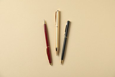 Photo of Stylish pens on beige background, flat lay