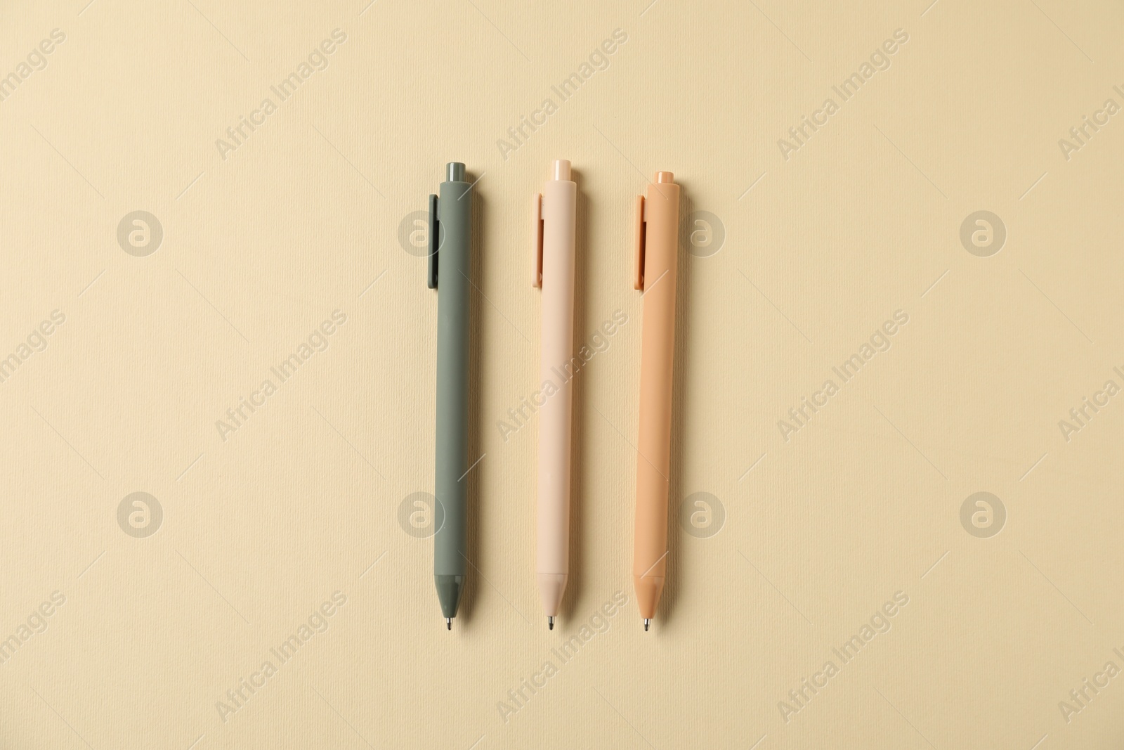 Stylish pens on beige background, flat lay Photo of Stylish pens on beige background, flat lay