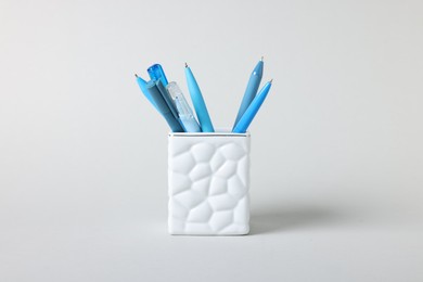 Photo of Ballpoint pens in holder on grey background