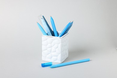 Photo of Ballpoint pens in holder on grey background