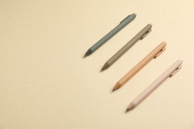 Photo of Set of stylish pens on beige background, above view. Space for text
