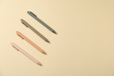 Photo of Set of stylish pens on beige background, flat lay. Space for text