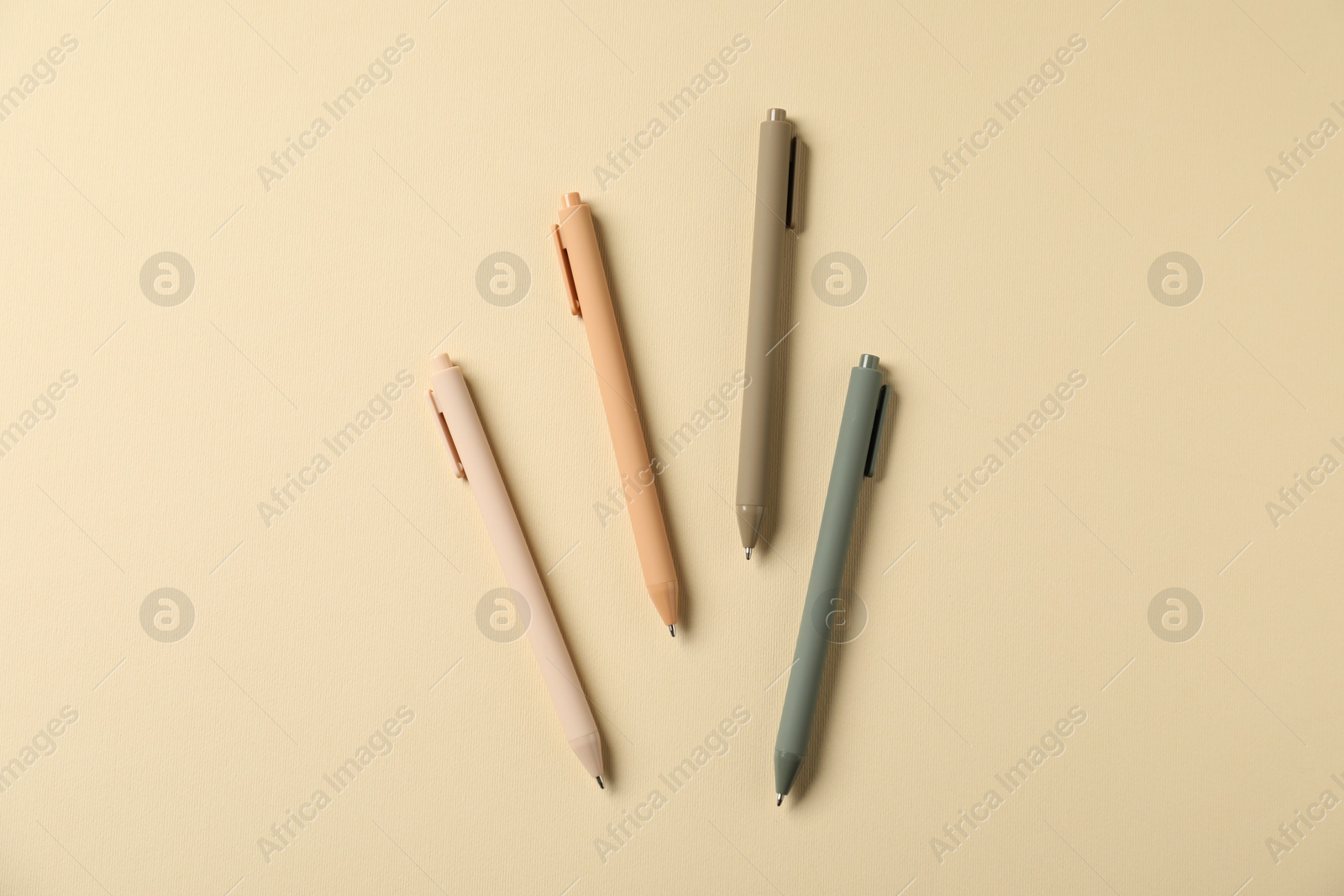 Stylish pens on beige background, flat lay Photo of Stylish pens on beige background, flat lay