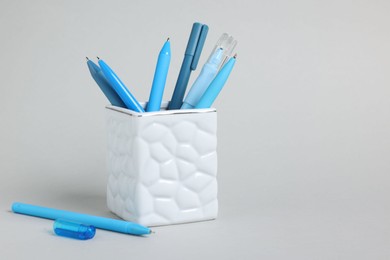 Photo of Ballpoint pens in holder on grey background, closeup. Space for text