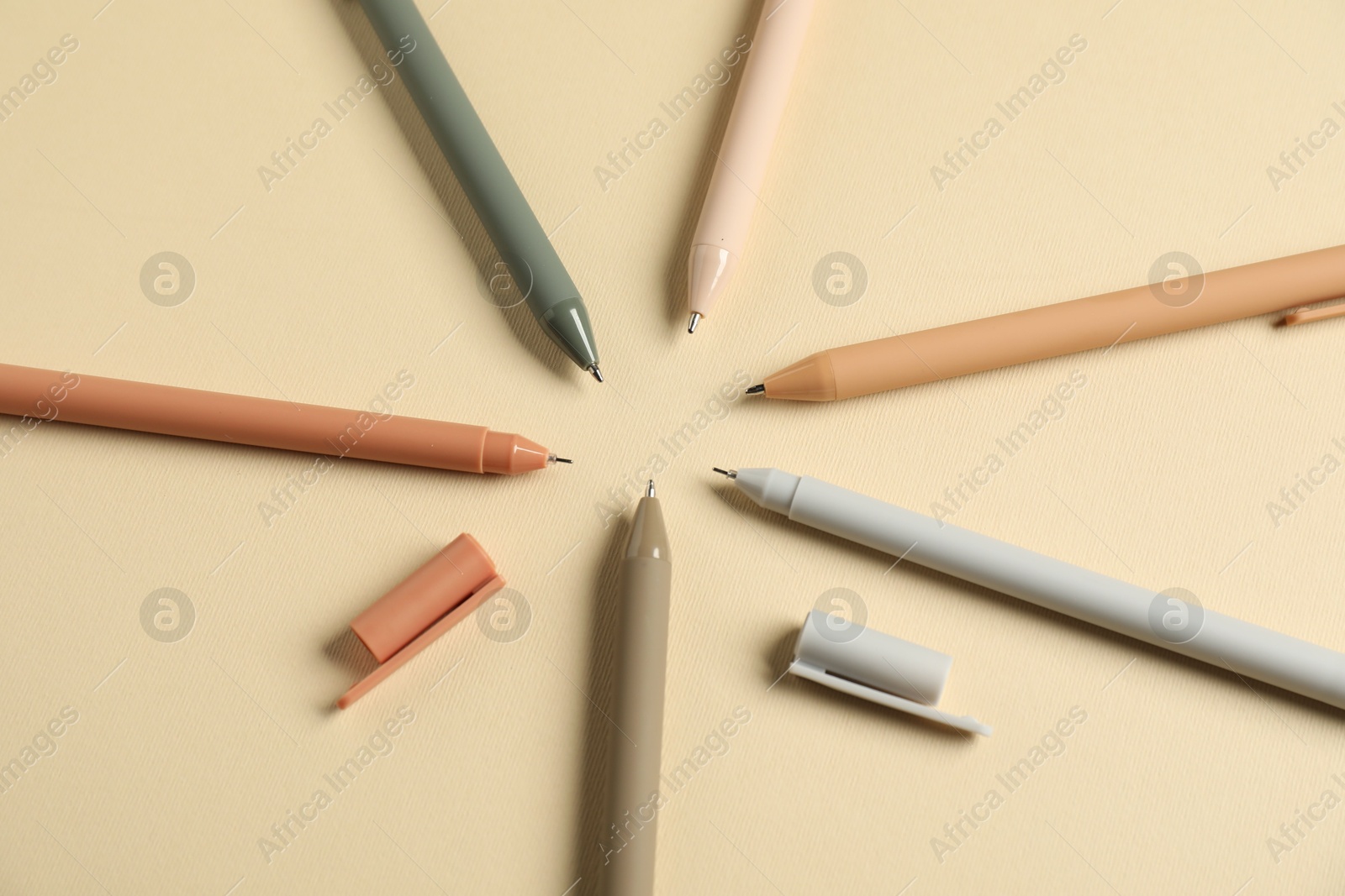 Set of stylish pens on beige background, flat lay Photo of Set of stylish pens on beige background, flat lay