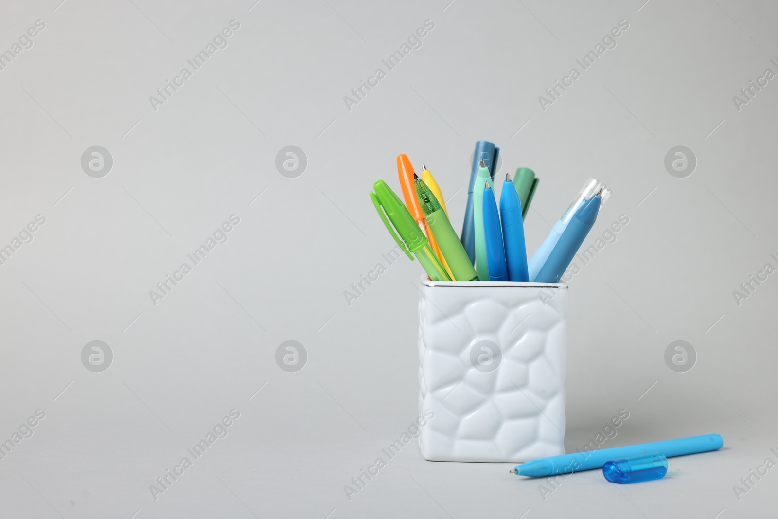 Ballpoint pens in holder on grey background. Space for text Photo of Ballpoint pens in holder on grey background. Space for text