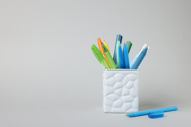Photo of Ballpoint pens in holder on grey background. Space for text