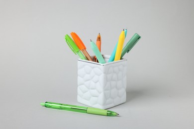 Photo of Ballpoint pens in holder on grey background, closeup