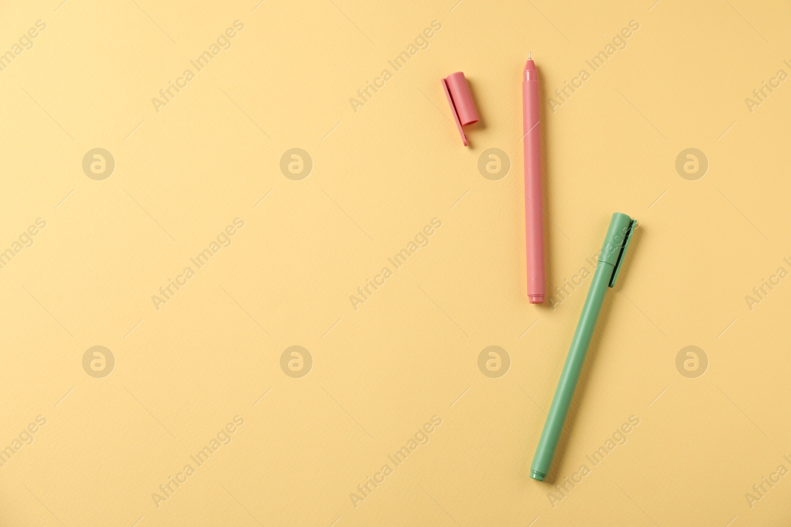 Stylish pens on yellow background, flat lay. Space for text Photo of Stylish pens on yellow background, flat lay. Space for text