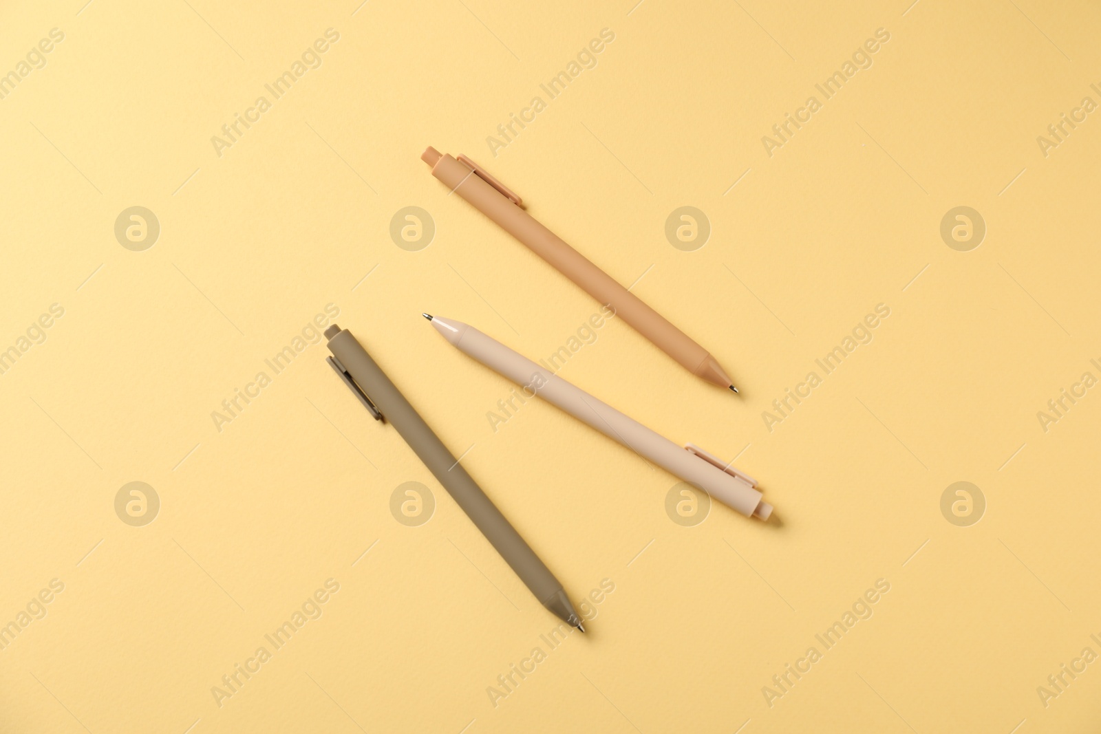 Stylish pens on yellow background, flat lay Photo of Stylish pens on yellow background, flat lay