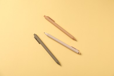 Photo of Stylish pens on yellow background, flat lay