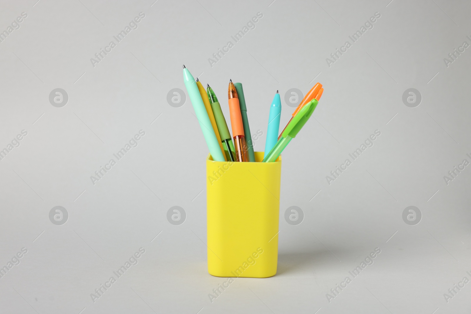 Ballpoint pens in holder on grey background Photo of Ballpoint pens in holder on grey background