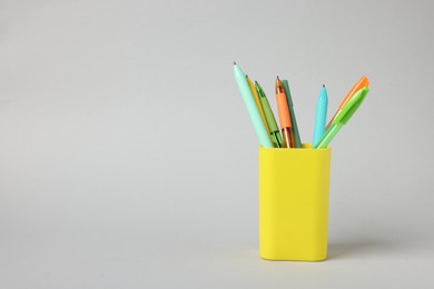Photo of Ballpoint pens in holder on grey background. Space for text
