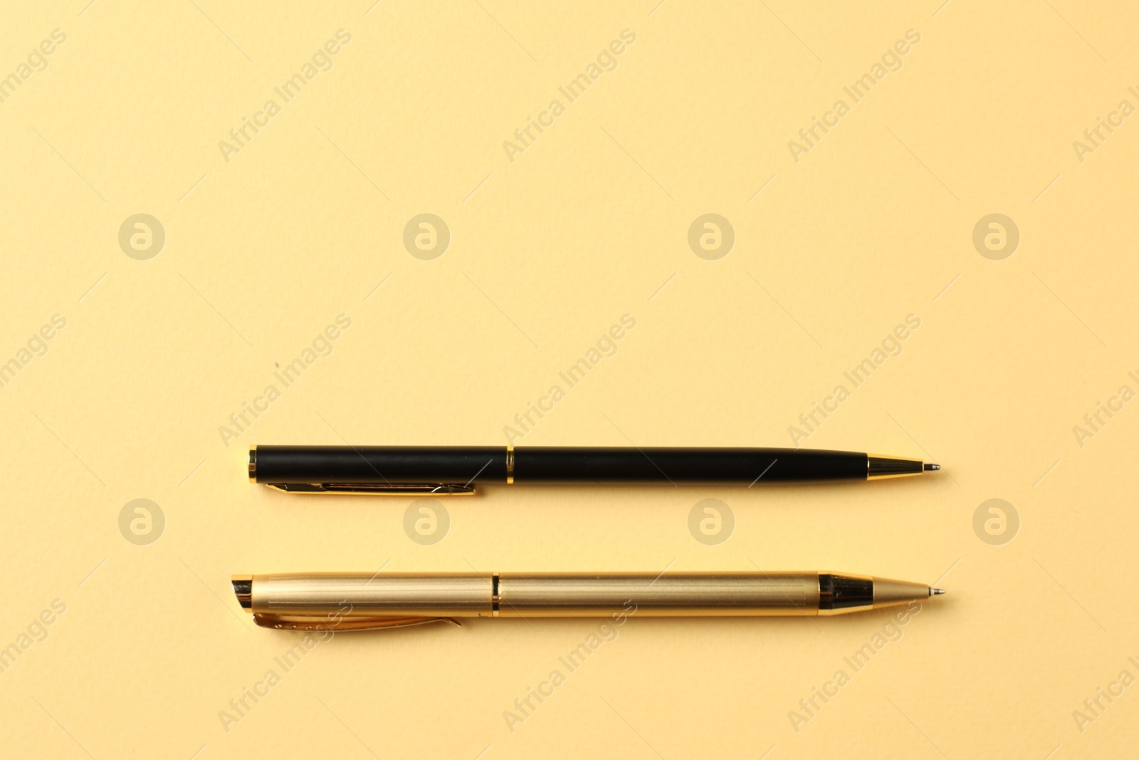 Stylish pens on yellow background, top view. Space for text Photo of Stylish pens on yellow background, top view. Space for text