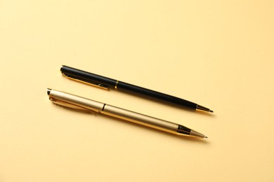 Photo of Stylish pens on yellow background, above view