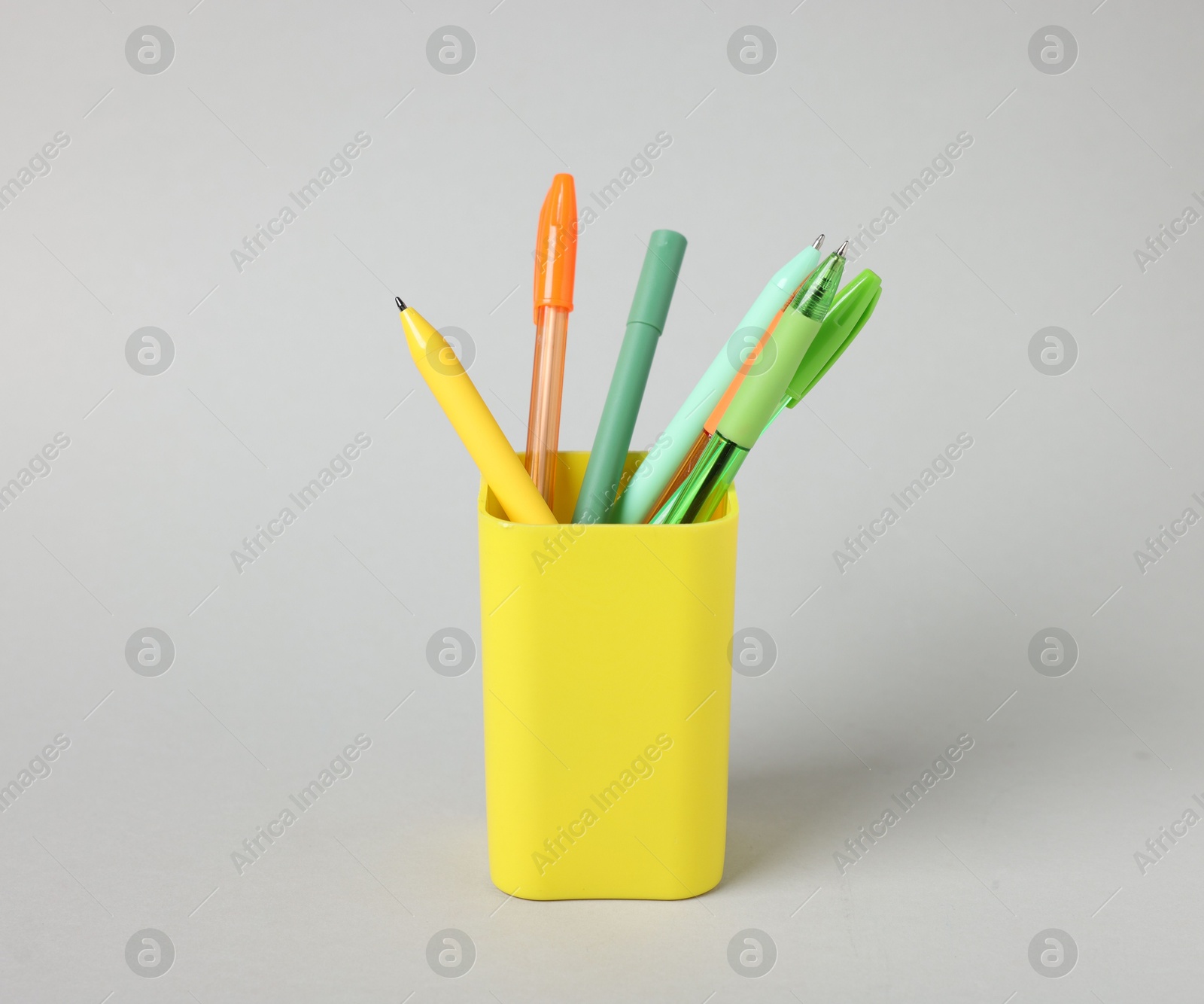 Ballpoint pens in holder on grey background Photo of Ballpoint pens in holder on grey background