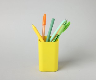 Photo of Ballpoint pens in holder on grey background