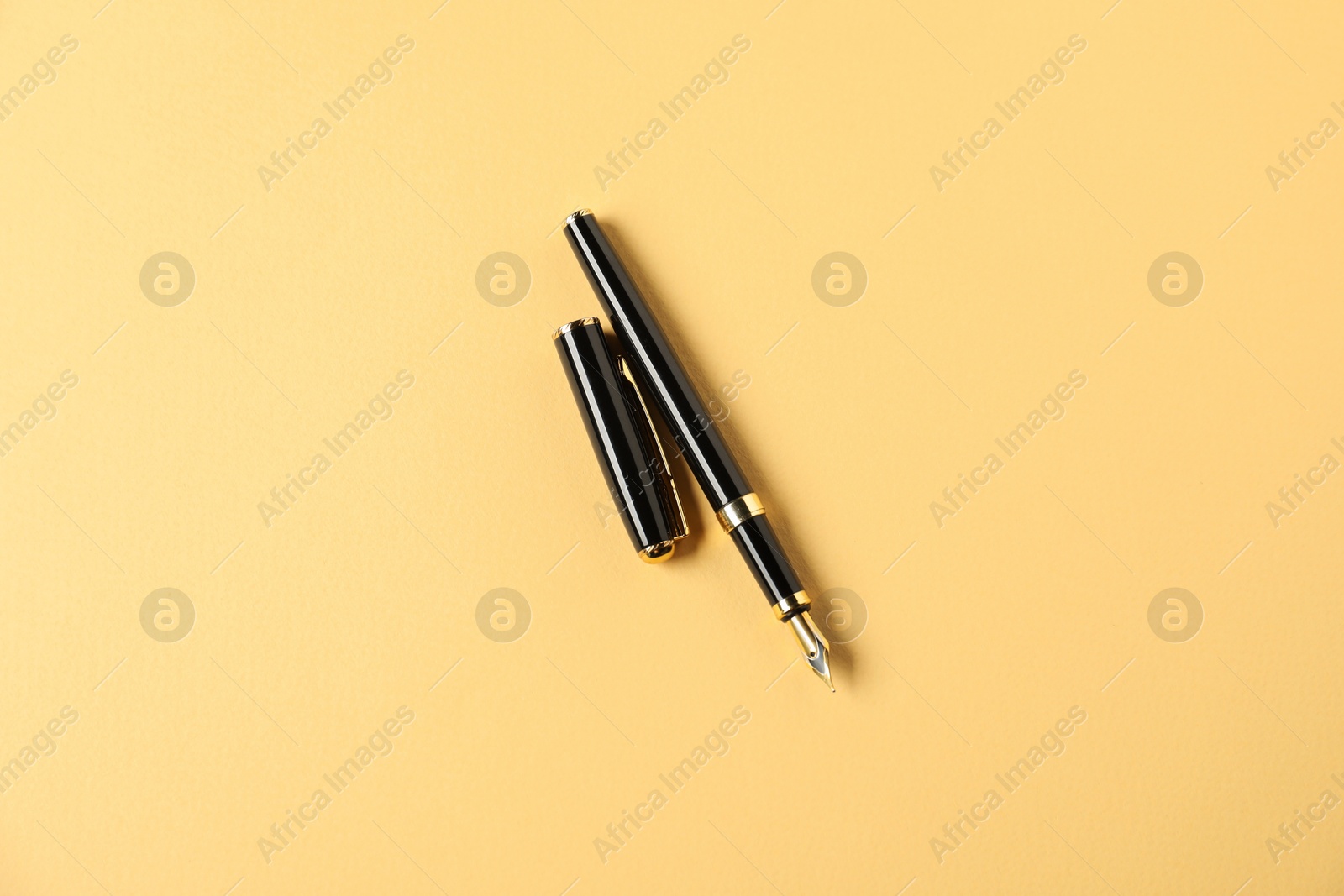 One fountain pen and lid on yellow background, top view Photo of One fountain pen and lid on yellow background, top view