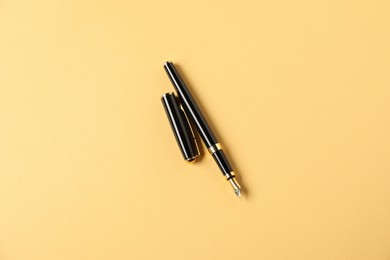 Photo of One fountain pen and lid on yellow background, top view