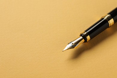 Photo of One fountain pen on yellow background, closeup. Space for text