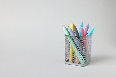 Photo of Ballpoint pens in holder on grey background, closeup. Space for text