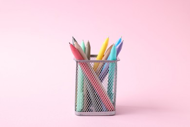 Photo of Ballpoint pens in holder on pink background, closeup