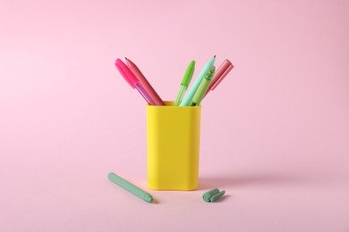 Photo of Ballpoint pens in holder on pink background, closeup
