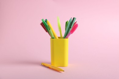Photo of Ballpoint pens in holder on pink background, closeup