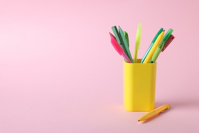 Photo of Ballpoint pens in holder on pink background, closeup. Space for text
