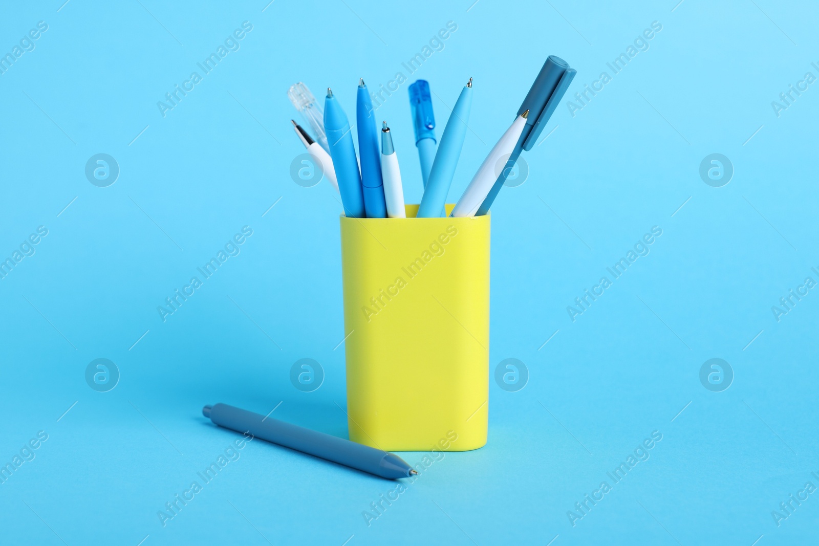 Ballpoint pens in holder on light blue background, closeup Photo of Ballpoint pens in holder on light blue background, closeup