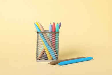 Photo of Ballpoint pens in holder on beige background, closeup