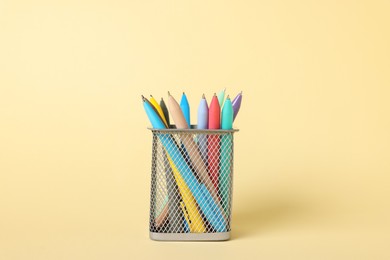 Photo of Ballpoint pens in holder on beige background, closeup
