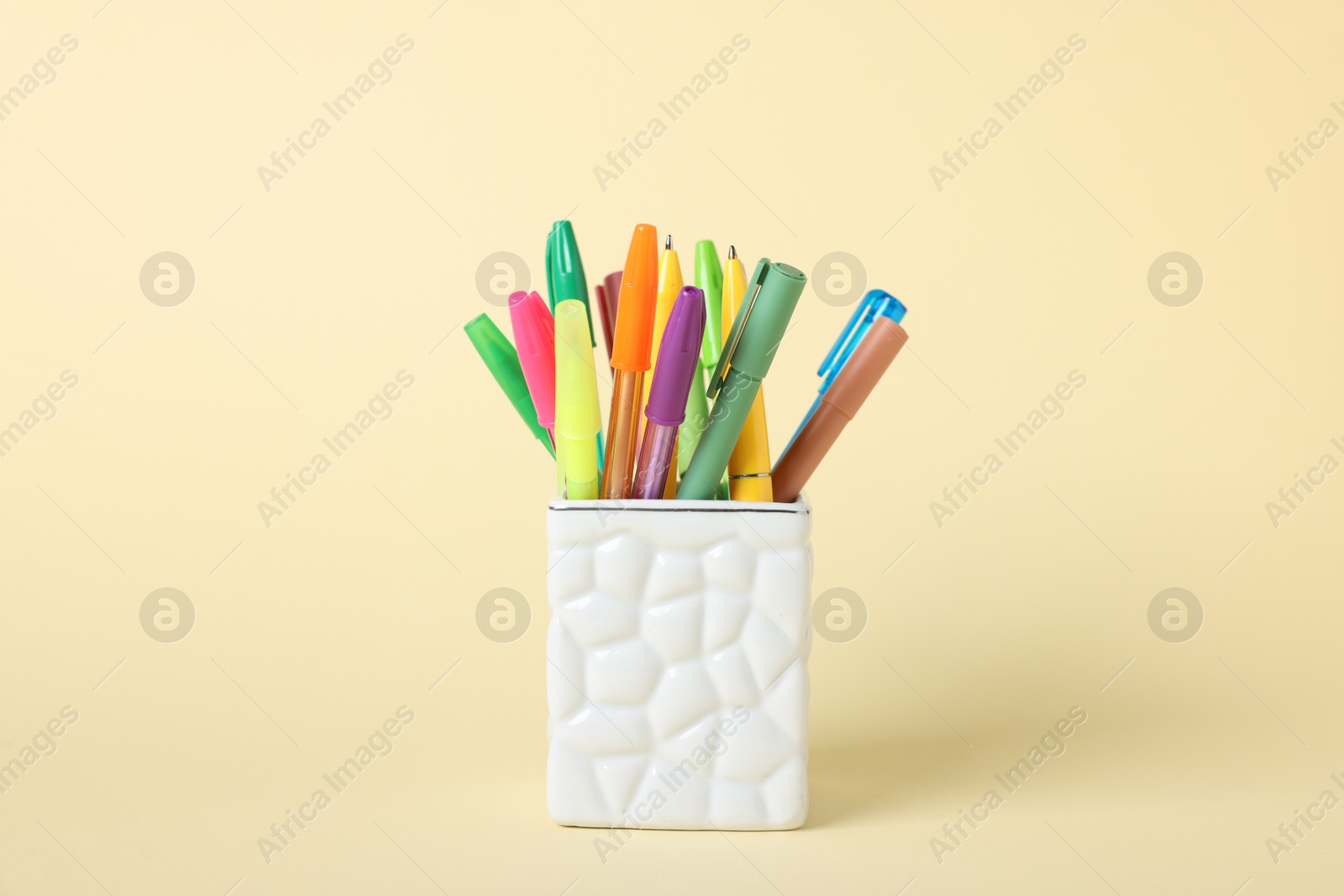 Ballpoint pens in holder on beige background, closeup Photo of Ballpoint pens in holder on beige background, closeup