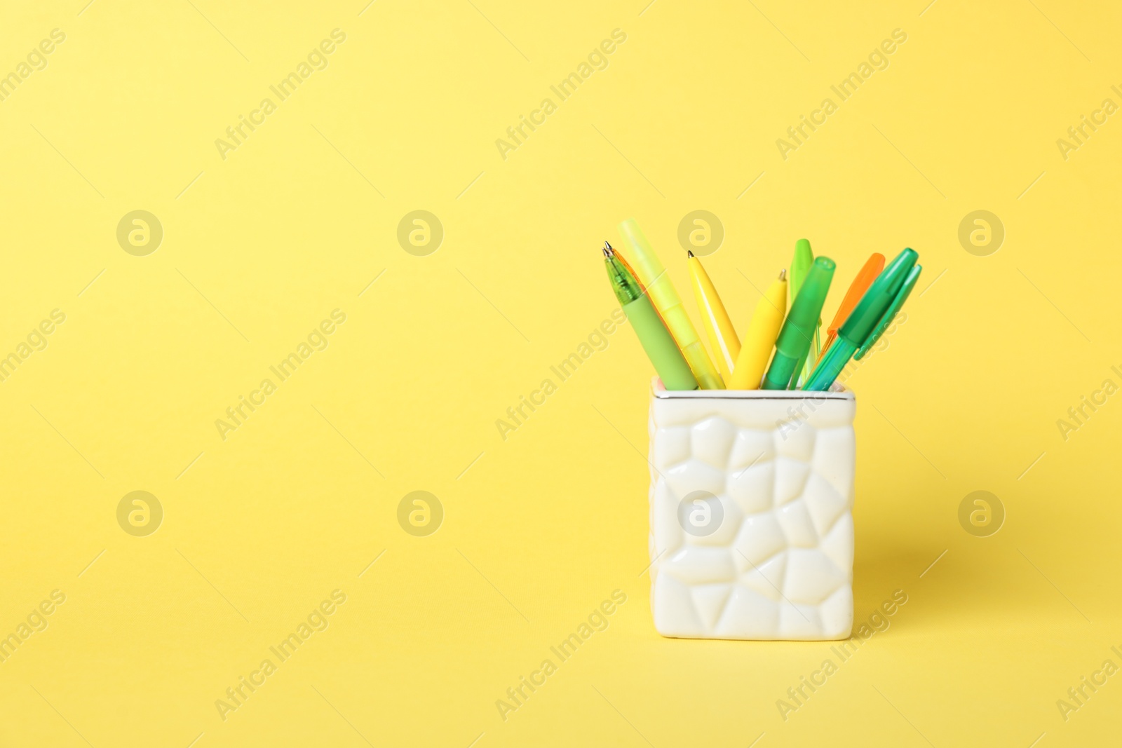 Ballpoint pens in holder on yellow background. Space for text Photo of Ballpoint pens in holder on yellow background. Space for text