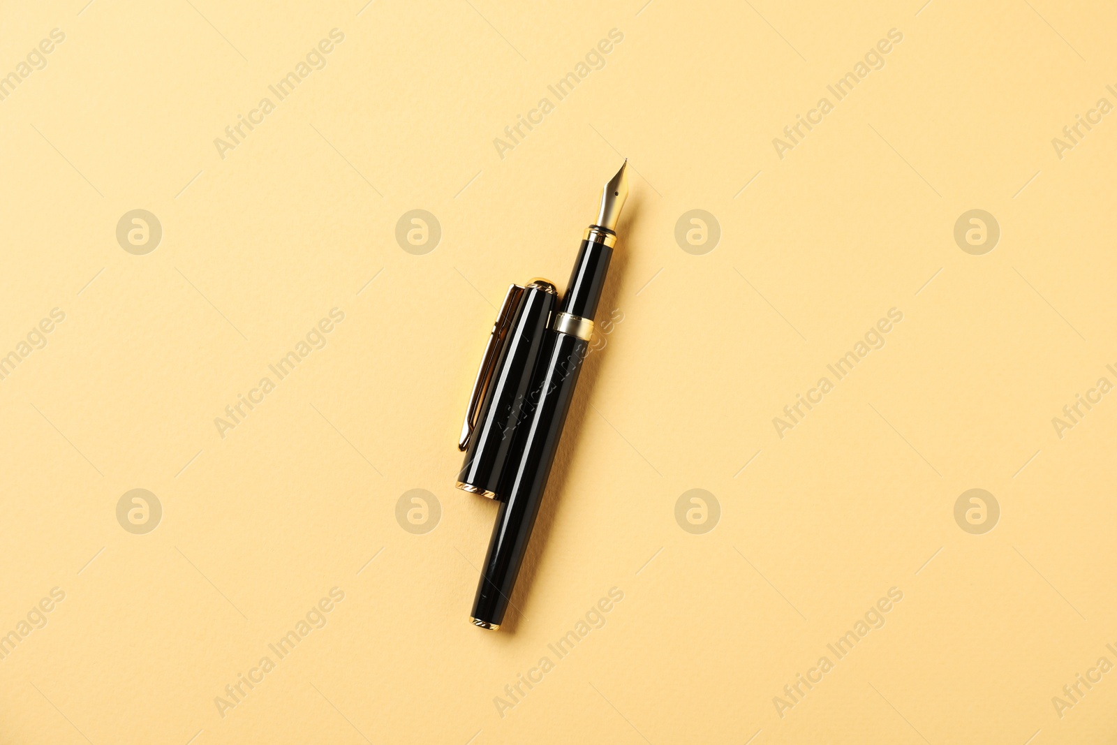 One fountain pen and lid on yellow background, top view Photo of One fountain pen and lid on yellow background, top view