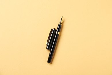Photo of One fountain pen and lid on yellow background, top view