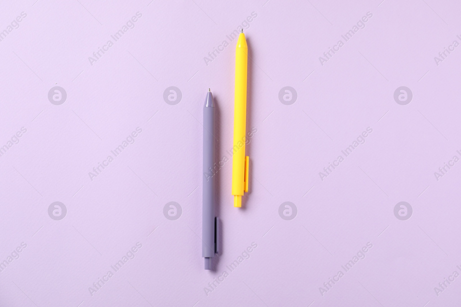 Photo of Stylish pens on violet background, top view