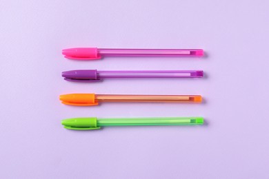 Photo of Stylish pens on violet background, flat lay