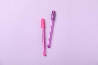 Photo of Stylish pens on violet background, top view