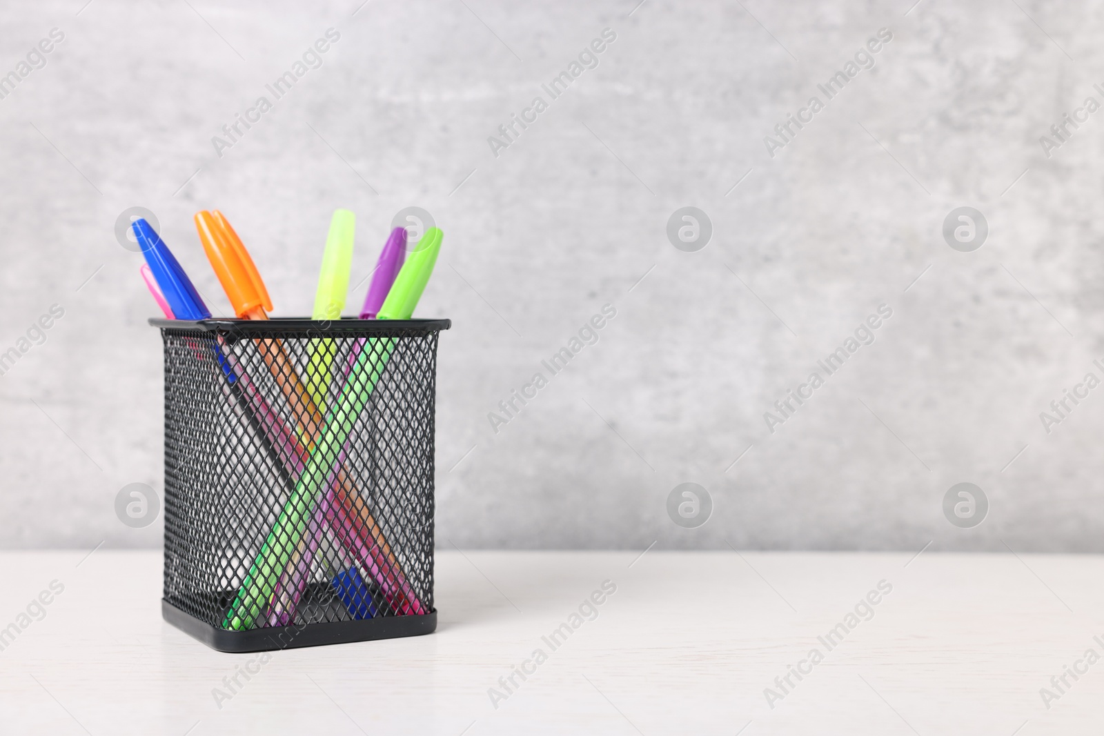Ballpoint pens in holder on light wooden table against grey background, closeup. Space for text Photo of Ballpoint pens in holder on light wooden table against grey background, closeup. Space for text