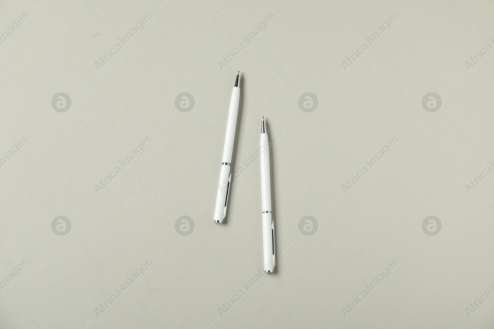 Stylish pens on grey background, flat lay Photo of Stylish pens on grey background, flat lay