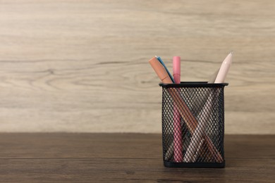 Photo of Ballpoint pens in holder on wooden table, closeup. Space for text