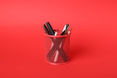 Photo of Ballpoint pens in holder on red background