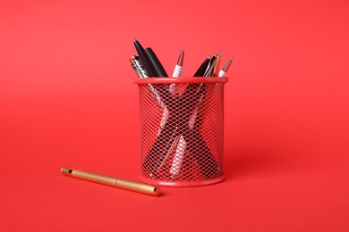 Photo of Ballpoint pens in holder on red background, closeup