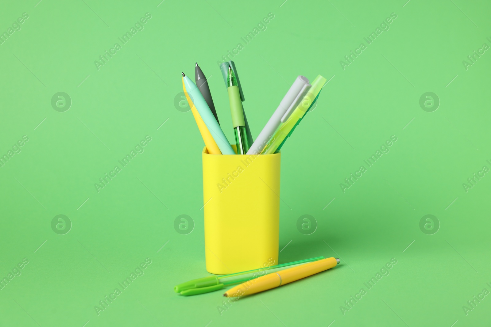 Ballpoint pens in holder on green background, closeup Photo of Ballpoint pens in holder on green background, closeup