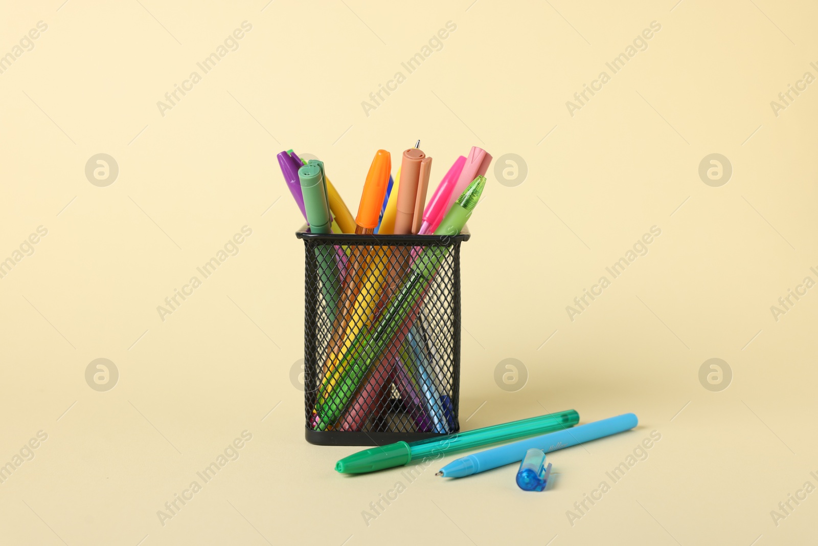 Ballpoint pens in holder on beige background Photo of Ballpoint pens in holder on beige background