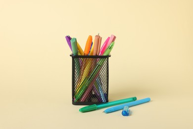 Photo of Ballpoint pens in holder on beige background