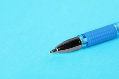 Photo of One ballpoint pen on light blue background, macro view. Space for text