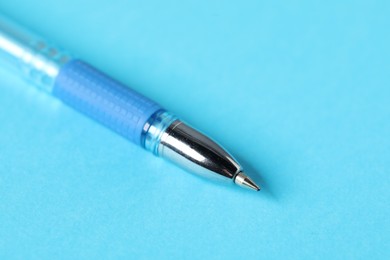 Photo of One ballpoint pen on light blue background, macro view. Space for text